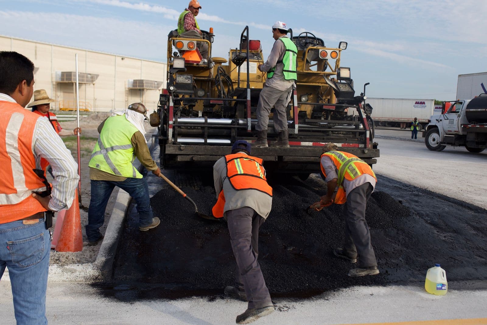 Crew and paving machine laying hot asphalt on a roadway